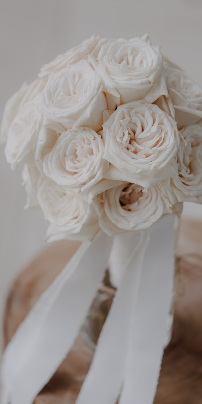 Brautstrauß aus vielen cremefarbenen Rosen uns weißem Band
